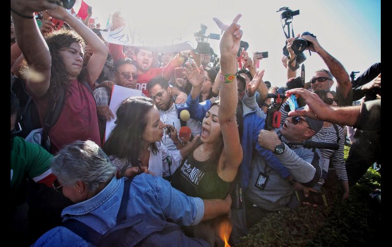 Unos manifestantes expulsan a una mujer de la protesta contra la presencia de migrantes centroamericanos.