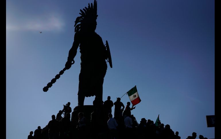 Manifestantes se congregan en una estatua de  Cuauhtémoc.