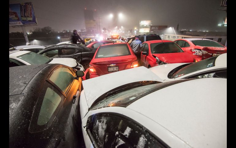 Conductores reaccionan y recogen algunas partes de sus vehÍculos tras un choque entre unos 40 automóviles en Saltillo, Coahuila, debido a la carretera congelada por el frío el 17 de enero.