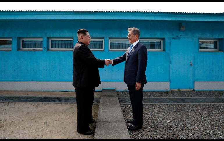 El líder norcoreano Kim Jong Un (i) y el presidente sudcoreano Moon Jae-in se saludan el 27 de abril en la línea de demarcación militar que divide a los dos países, en el marco de la histórica cumbre de los dirigentes. AFP/Korea Summit Press