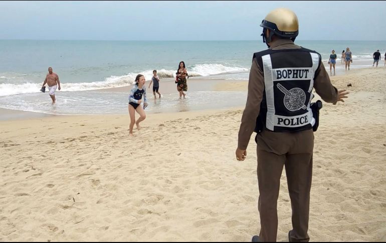 Un policía advierte a bañistas de la prohibición de baño en la playa en la isla Koh Samui debido al tiempo en la provincia de Surat Thani. EFE/S. Chareonjai