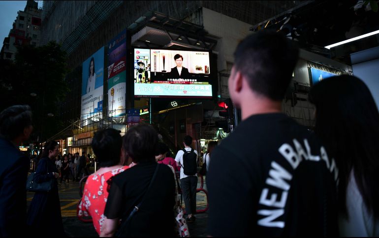 Peatones miran un monitor que muestra la noticia del anuncio de Carrie Lam en Hong Kong. AFP/A. Wallace