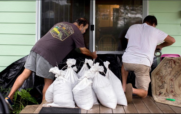 Dos personas colocan sacos de arena en la entrada de una vivienda ante la cercanía del huracán. AP/S. Morton