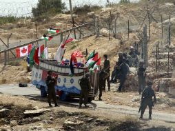 • Palestinos protestan con una representación de la Flotilla de la Libertad, en la valla entre Israel y Cisjordania. REUTERS  /