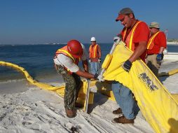 Trabajadores colocan contenedores de petróleo, que sigue expandiéndose por el Golfo de México. AFP  /