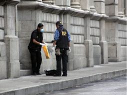 Dos miembros del Ministerio Público recogen evidencias en las afueras de la sede del Congreso de Guatemala. EFE  /