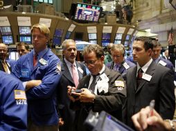 Agentes de bolsa y especialistas trabajan el piso de remates de la Bolsa de Nueva York. AP  /