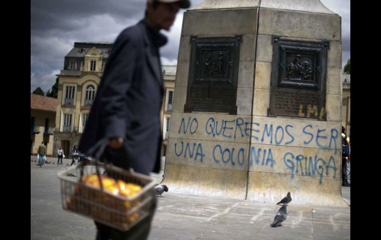 Un vendedor pasa frente a un monumento en Plaza Bolívar donde se lee el rechazo a las relaciones con Estados Unidos. AFP  /