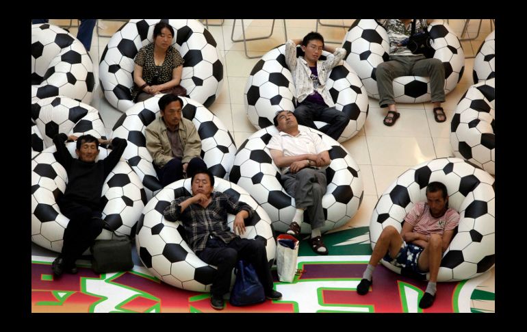 Residentes de China descansan entre dos partidos de futbol de la Copa en Sudáfrica. Mientras, su nación espera crecer 10% este año. AP  /