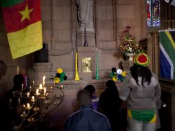 Aficionados sudafricanos oran a una figura de Jesucristo adornada con vuvuzelas y banderas en la Catedral de Pretoria. AP  /