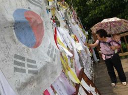 En la imagen, una mujer coloca un listón con un deseo sobre una valla, en la zona fronteriza. AP  /