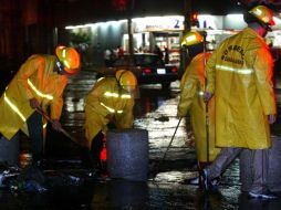 Bomberos tapatíos trabajan en el retiro de la basura que arrastró la corriente, tras la tormenta de anoche. E. BARRERA  /