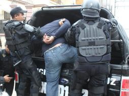 Policías conducen a una de las personas armadas que pretendían ingresar a la sede del Instituto Electoral Veracruzano. EL UNIVERSAL  /