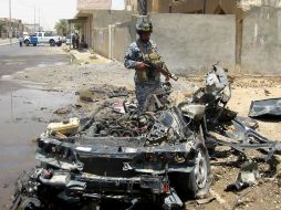 Un policía iraquí inspecciona un vehículo destruido por una bomba en el centro de Tikrit, a 160 kilómetros de Bagdad. AFP  /