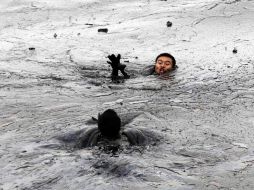 Un bombero corre a rescatar a su colega atrapado (izquierda) por la fuga de crudo en la Bahía de Dalian. AP  /