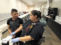 Una oficial de Maricopa, Arizona, ayuda a un detenido en la captura de las huellas para verificar su condición migratoria. AP  /