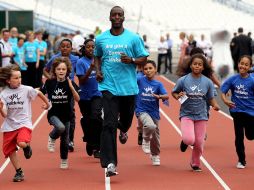 El medallista olímpico Michael Johnson (centro) corre con un grupo de niños en el Estadio Olímpico Londres 2012. AP  /