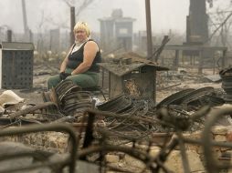 Imagen en la que una mujer rubia observa cómo el fuego ha devorado con todo a su paso en Rusia. AFP  /