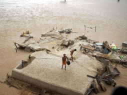 Dos hombres sobreviven en el techo de su casa, lo único de la vivienda que queda fuera del agua, en Pakistán. AP  /