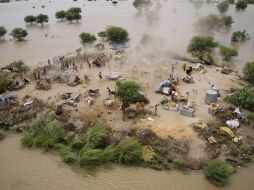 Un helicóptero deja caer suministros a aldeanos que se resguardan en un montículo. AP  /