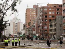 Bomberos limpian la zona de la explosión que dañó decenas de edificios. EFE  /