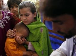 Una niña anima a su hermano mientras esperan atención médica en un centro de salud en Charsadda, Pakistán. REUTERS  /