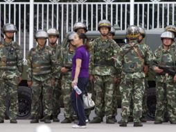 Una mujer se acerca al lugar donde se encuentra un grupo de militares chinos en Urumqui. EFE  /