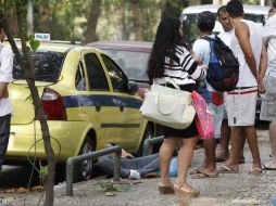 Un grupo de personas observa el cuerpo de la mujer que murió durante un enfrentamiento. EFE  /
