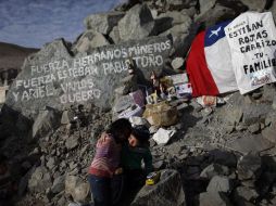 Un menor abraza a su hermana junto a un altar en honor a los trabajadores atrapados en la mina San José. AP  /