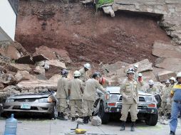 Protección Civil inspecciona el colapso de un muro que cayó sobre 15 automóviles, en un estacionamiento de Tegucigalpa. EFE  /