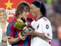 El capitán del FC Barcelona, Carles Puyol (iz) muestra el trofeo conseguido al delantero brasileño del AC. Milan, Ronaldinho Gaucho.EFE  /