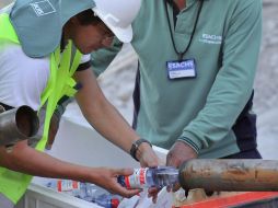 Rescatistas colman un tubo con agua embotellada que llegará a los mineros mediante la perforación de abastecimiento. AFP  /