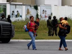 Mujeres con niños pasan hoy junto a soldados, quienes resguardan la escena de un enfrentamiento en Monterrey. REUTERS  /