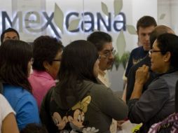 Los pasajeros afectados por el cese de actividades de Mexicana esperan información adicional en los mostradores. AFP  /