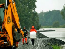 Hombres arreglando los daños que dejó la inundación en Uruguay. AFP  /