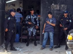 Policías custodian la entrada a la fábrica de zapatos que se encuentra en el marginal barrio San Francisco de San Pedro Saula. EFE  /