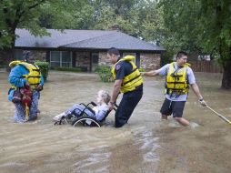 Rescatistas ayudan a una mujer de la tercera edad en silla de ruedas, a escapar de las inundaciones en Texas. AP  /