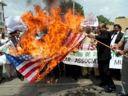 Manifestantes pakistaníes queman una bandera durante una protesta en la ciudad de Mahmud Raqi. EFE  /