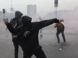 Un manifestante arroja una piedra contra vehículos de la Policía durante la marcha en memoria de las víctimas dictadura militar. AFP  /