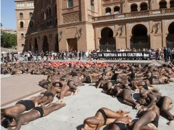 Cuerpos semidesnudos de personas posaron semidesnudos formando la figura de un toro sangrante. EFE  /