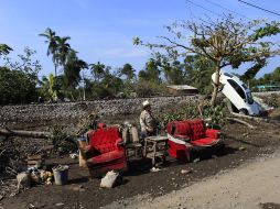 Un habitante de Samoral, en Veracruz, camina entre muebles llenos de lodo y un carro dañado por las inundaciones. REUTERS  /