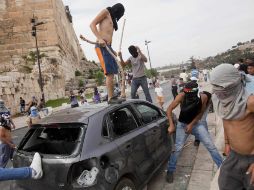Palestinos arruinan un automóvil durante el enfrentamiento contra policías israelíes, en Jerusalén. AP  /