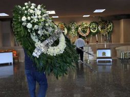 Un hombre carga un arreglo de flores para el funeral de Prisciliano Rdríguez. AP  /