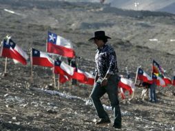 Un familiar de uno de los mineros atrapados camina junto a banderas chilenas. EFE  /