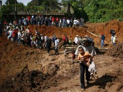 Un hombre carga a un niño durante la evacuación en Santa María Tlahuitoltepec, tras el deslave que afectó varias viviendas. AP  /