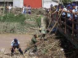 Militares y policías estatales realizan labores de limpieza debajo de un puente en Oaxaca. AP  /
