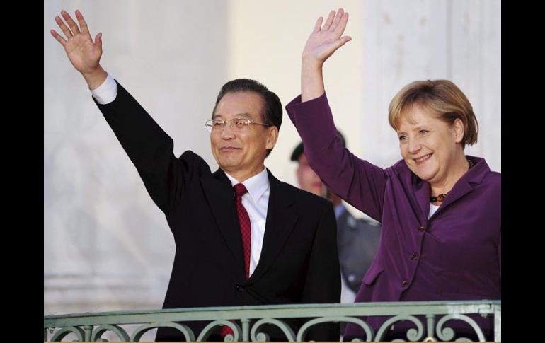 Angela Merkel (der.) y el primer ministro chino, Wen Jiabao (izq.), saludan desde un balcón del castillo de Meseberg, Alemania. EFE  /
