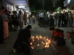 Compañeros de Lucila Quintanilla, la joven caída por fuego de pistoleros, prenden veladoras en su memoria. AP  /