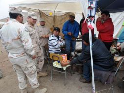 Familiares de los mineros atrapados y soldados chilenos conversan. AFP  /
