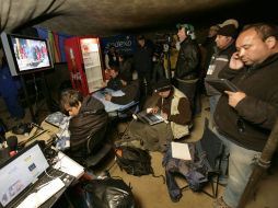 Periodistas observan hoy la transmisión en vivo de los preparativos del rescate de los mineros. AP  /